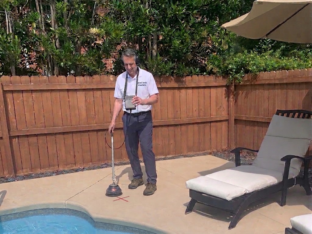 Pool Leak Masters technician using acoustic equipment to pinpoint a pool leak beside a backyard pool